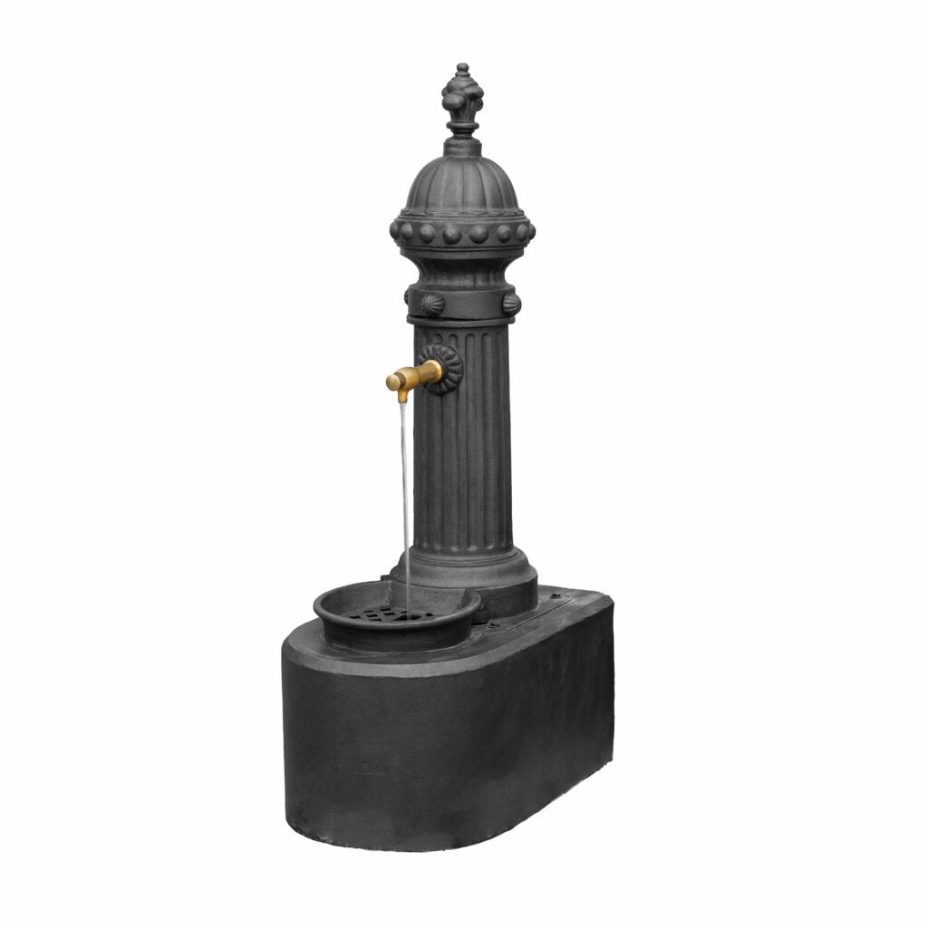 Una clàssica font daigua negra exterior amb un disseny de columna alta i decorativa. Disposa dun broc de llautó des del qual saboca aigua en un bol sobre una base rectangular. L'estil general és vintage o tradicional.