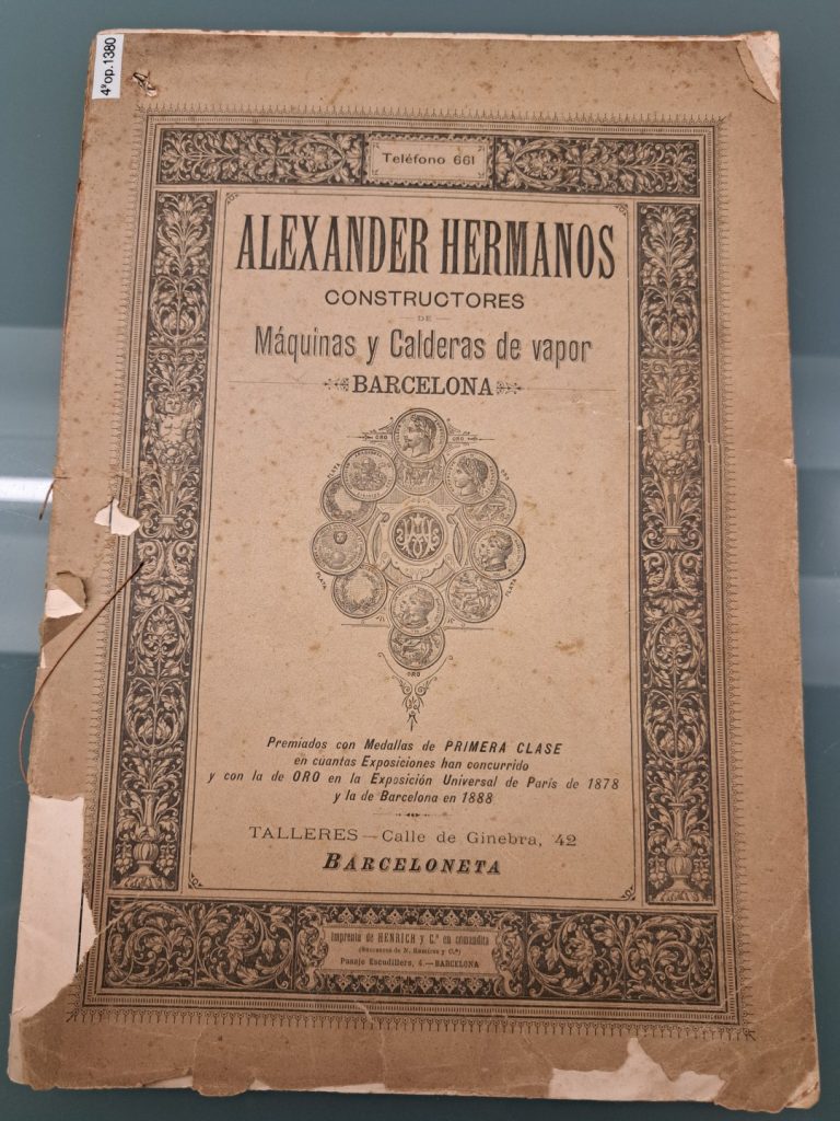Una coberta antiga i desgastada d'un catàleg o fullet titulat Alexander Hermanos Constructores Máquinas y Calderas de vapor, Barcelona amb vores ornamentades i elements decoratius en text en castellà.